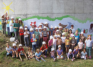 A number of children in front of a wall